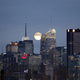 A full moon rises behind the skyline of midtown Manhattan in New York, November 21, 2010. The New York Times building sits at left and the new Bank of America tower is in the center, in front of the moon. REUTERS/Gary Hershorn